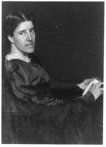 Charlotte Perkins Gilman photographed sitting with a notebook in hand. 