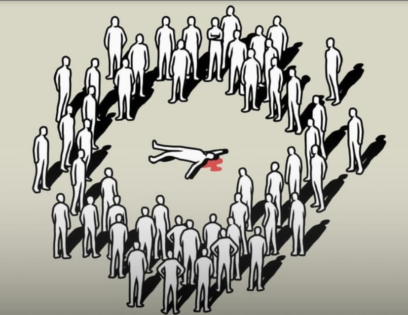 A large group of people standing around an injured person in the center of the circle.