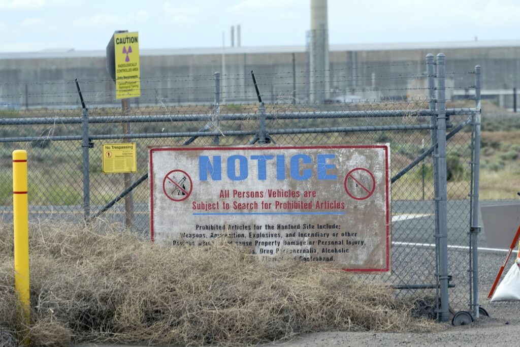 A weathered notice sign posted outside the Los Alamos site, bearing official government markings. The text shows that the are is restricted and warns against unauthorized entry.